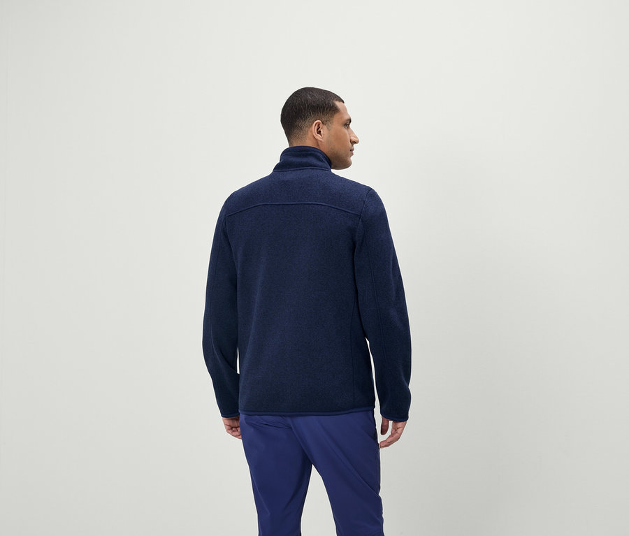 Un homme porte un pull bleu à fermeture éclair et un pantalon bleu.