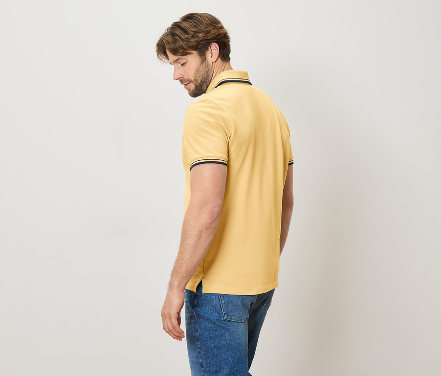 Homme vu de dos portant un polo jaune et un jean bleu.