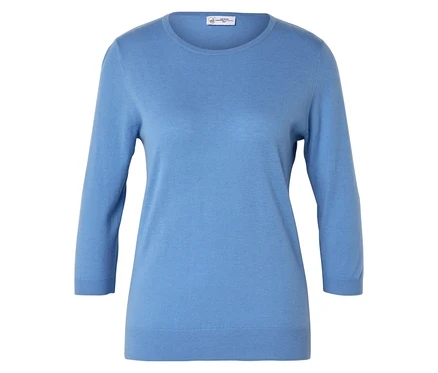 Un pull bleu clair à manches trois-quarts est posé sur une surface blanche.