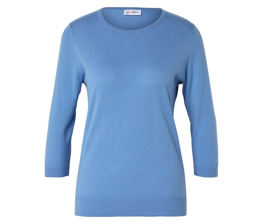 Un pull bleu clair à manches trois-quarts est posé sur une surface blanche.