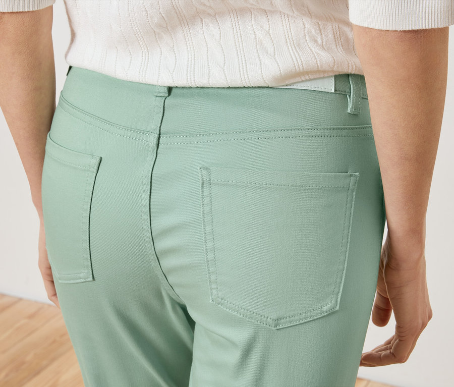 Gros plan sur le dos d'une femme portant un pantalon vert clair et un haut blanc.