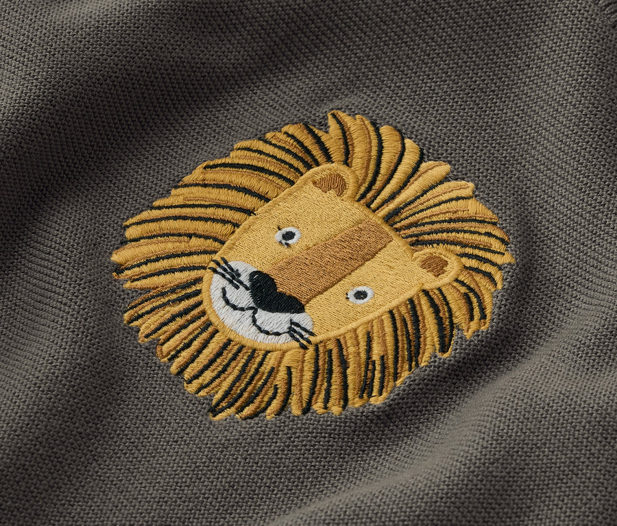 Sur un tissu gris est cousu un lion.