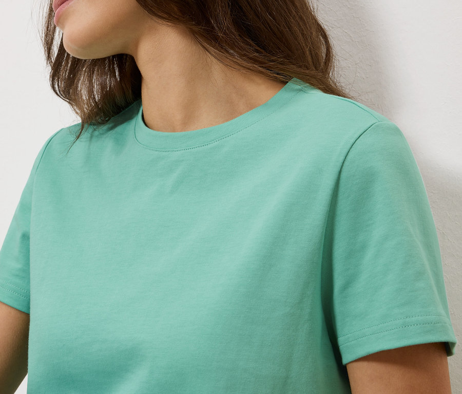Gros plan d'une femme portant un t-shirt turquoise clair.