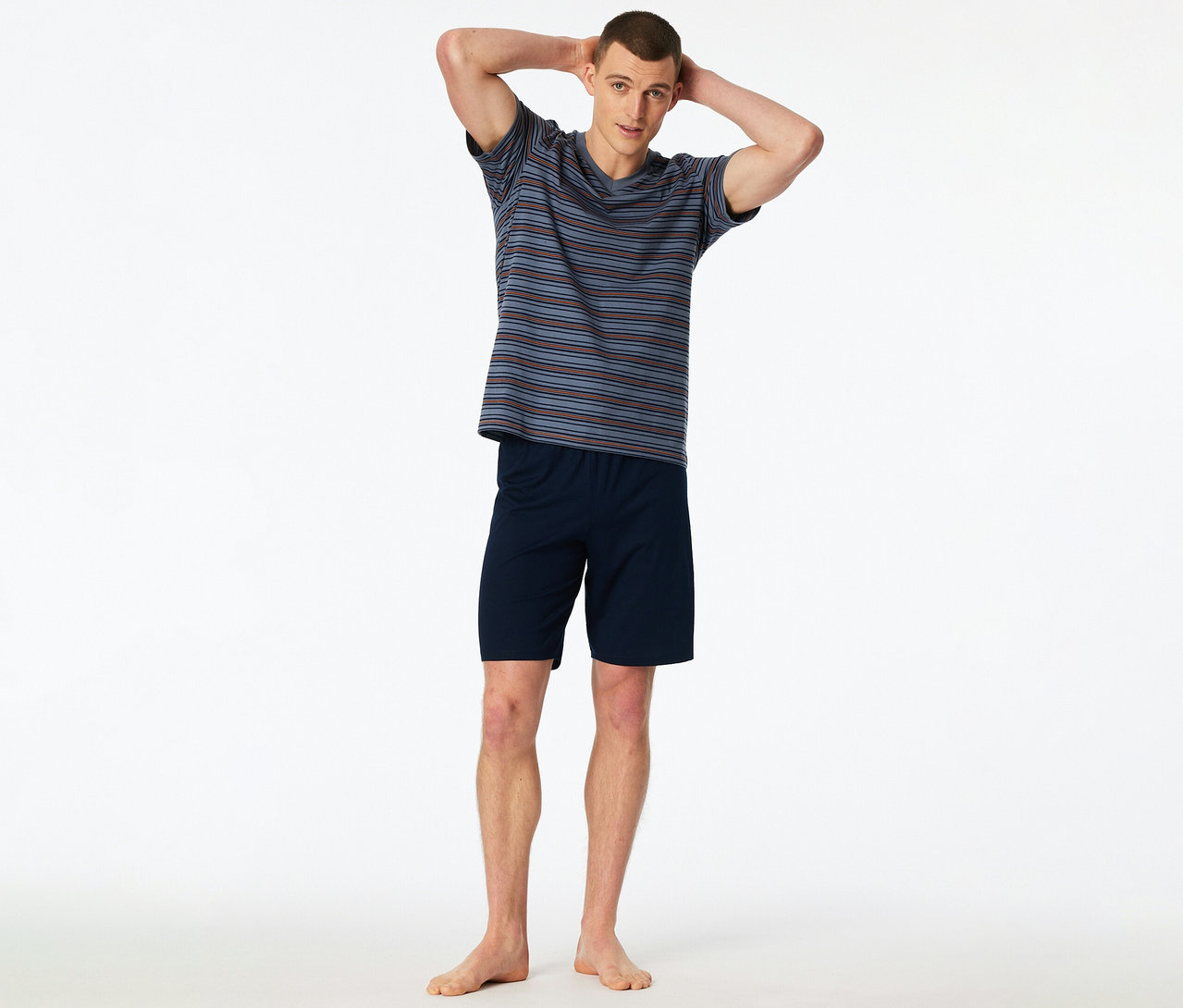 Un homme debout, les mains derrière la tête, porte un set shorty SCHIESSER rayé.