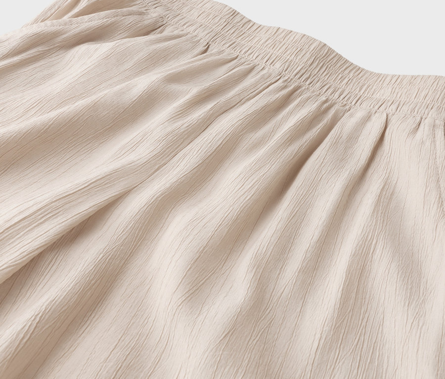 Gros plan sur le haut d'un pantalon beige avec une taille élastique et une poche latérale.