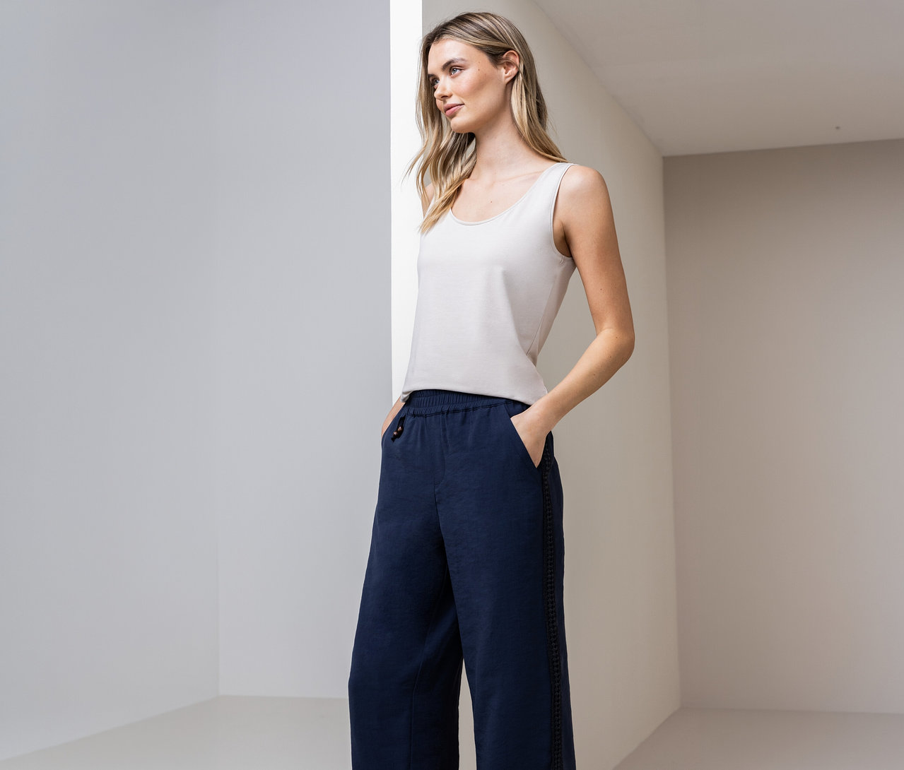 Femme portant un haut classique Street One et un pantalon bleu, les mains dans les poches, devant un mur.