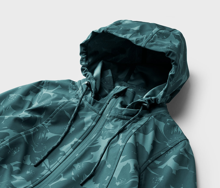Gros plan d'une veste turquoise à motif floral avec capuche et fermeture éclair sur fond blanc.