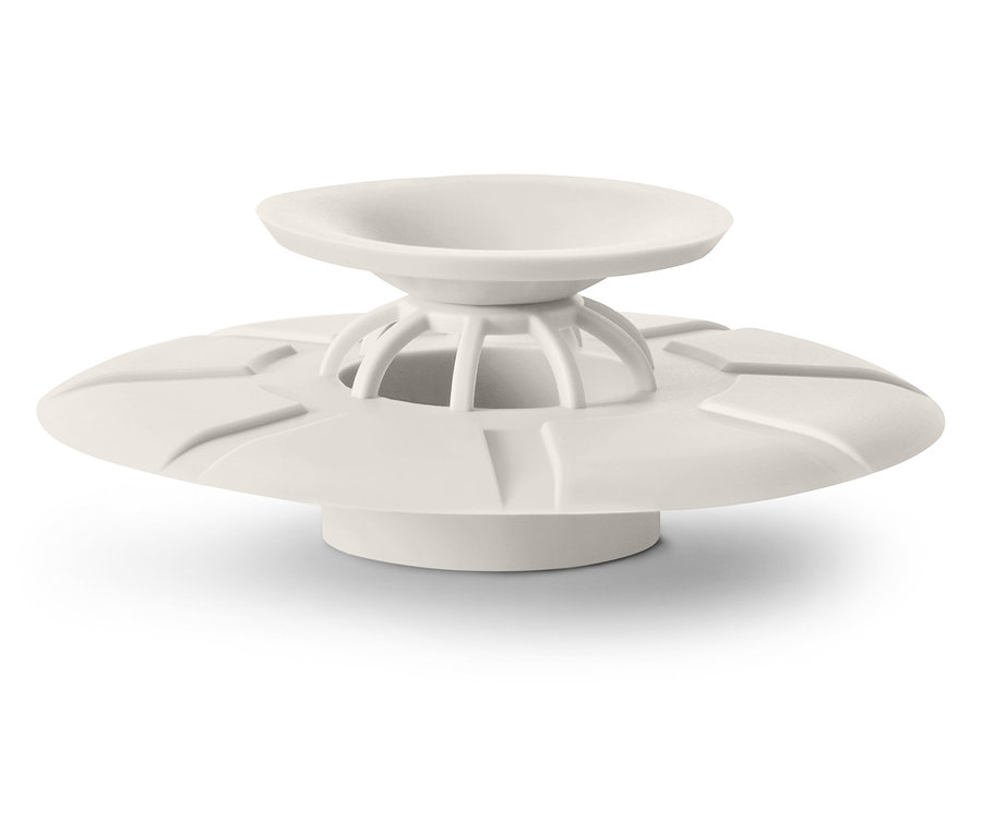 Un bouchon de drain couleur crème avec un design en forme d'assiette repose sur une surface blanche.