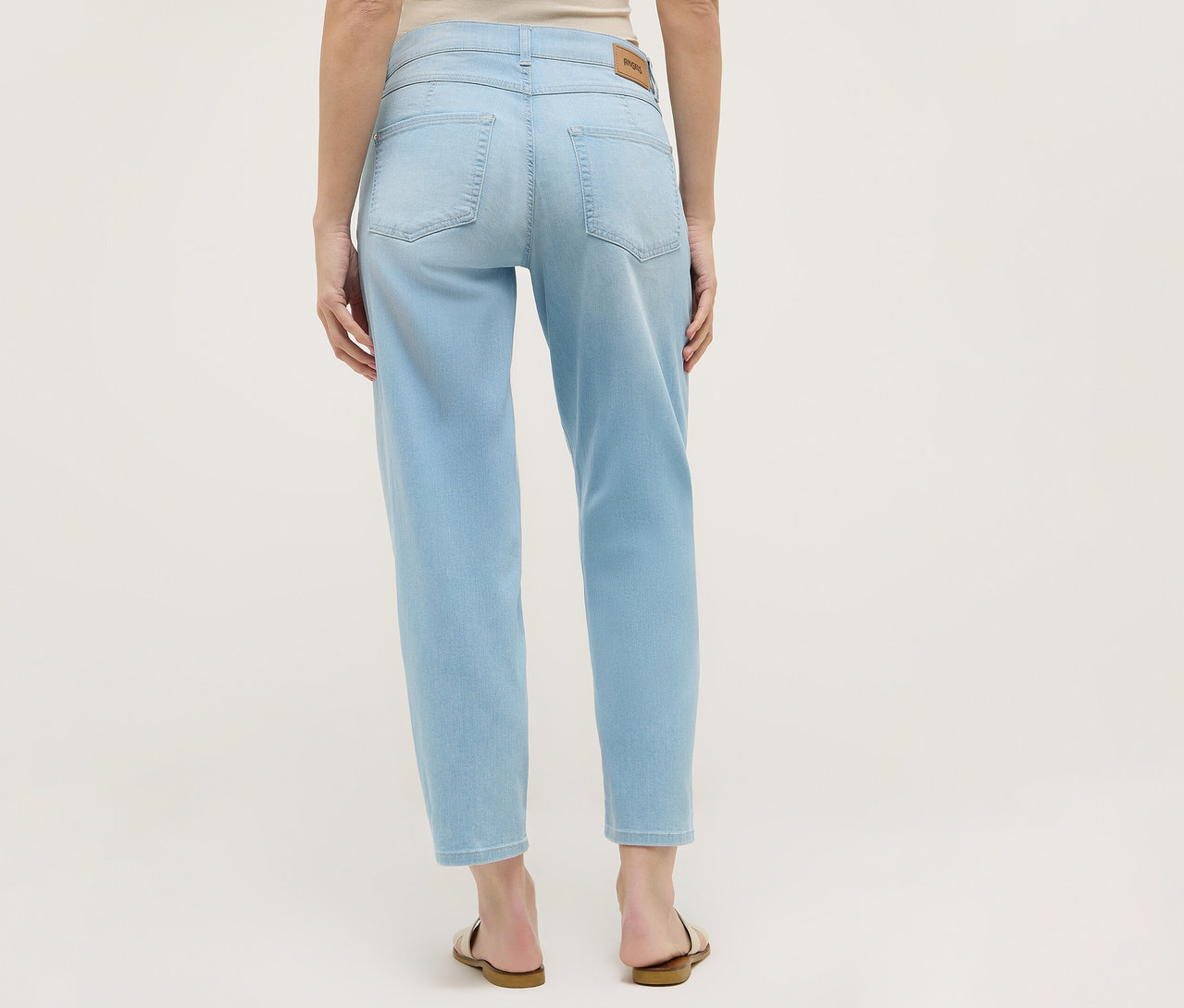 Vue arrière d'une femme portant un jean Angels Denim « Evy Cool » O-Shape bleu clair et des sandales.