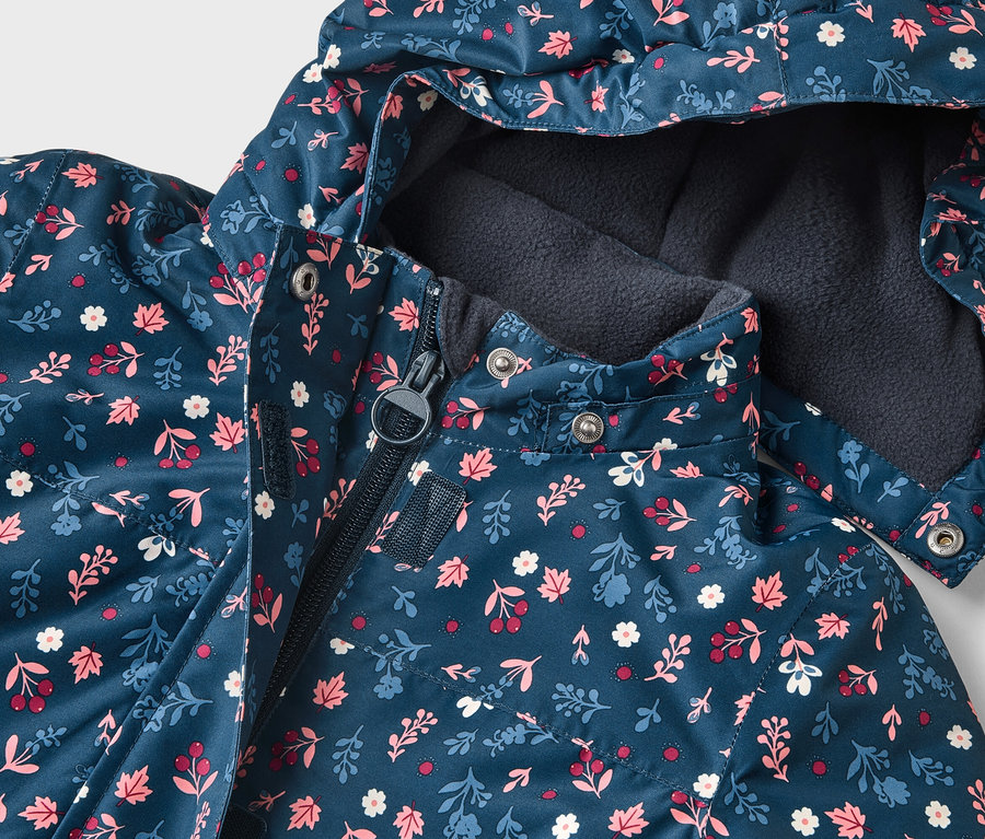 Gros plan d'une veste bleu marine à motifs floraux avec capuche, partiellement fermée par une fermeture éclair.