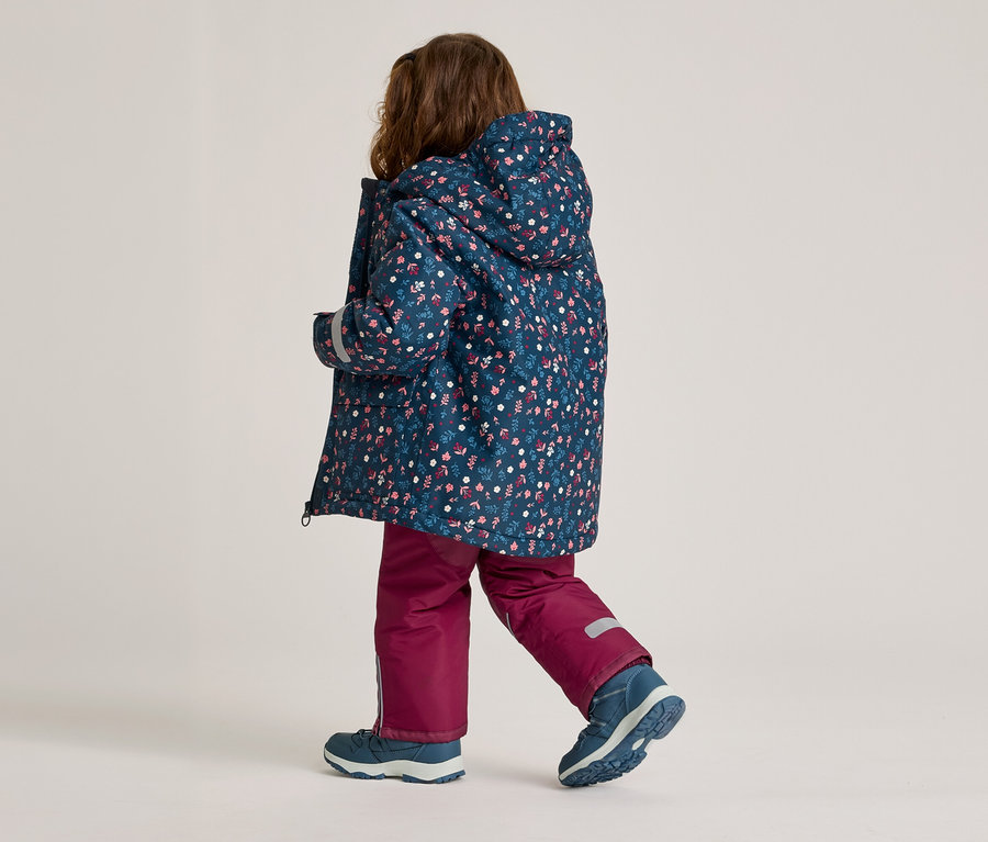 Enfant vu de dos portant une veste à capuche à motifs floraux, un pantalon bordeaux et des chaussures bleues.