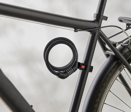 Gros plan d'un cadre de vélo noir avec un antivol à combinaison en spirale fixé au cadre.
