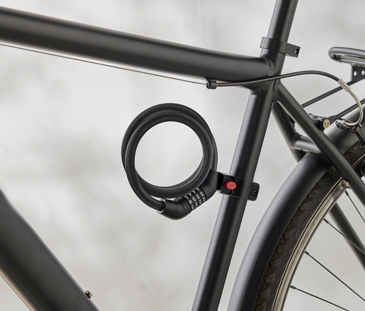 Gros plan d'un cadre de vélo noir avec un antivol à combinaison en spirale fixé au cadre.