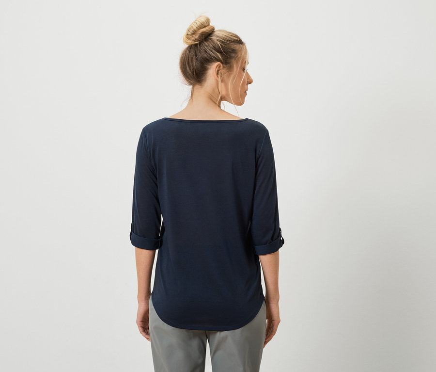 Vue arrière d'une femme avec un chignon portant un T-shirt bleu marine à manches longues et un pantalon gris.