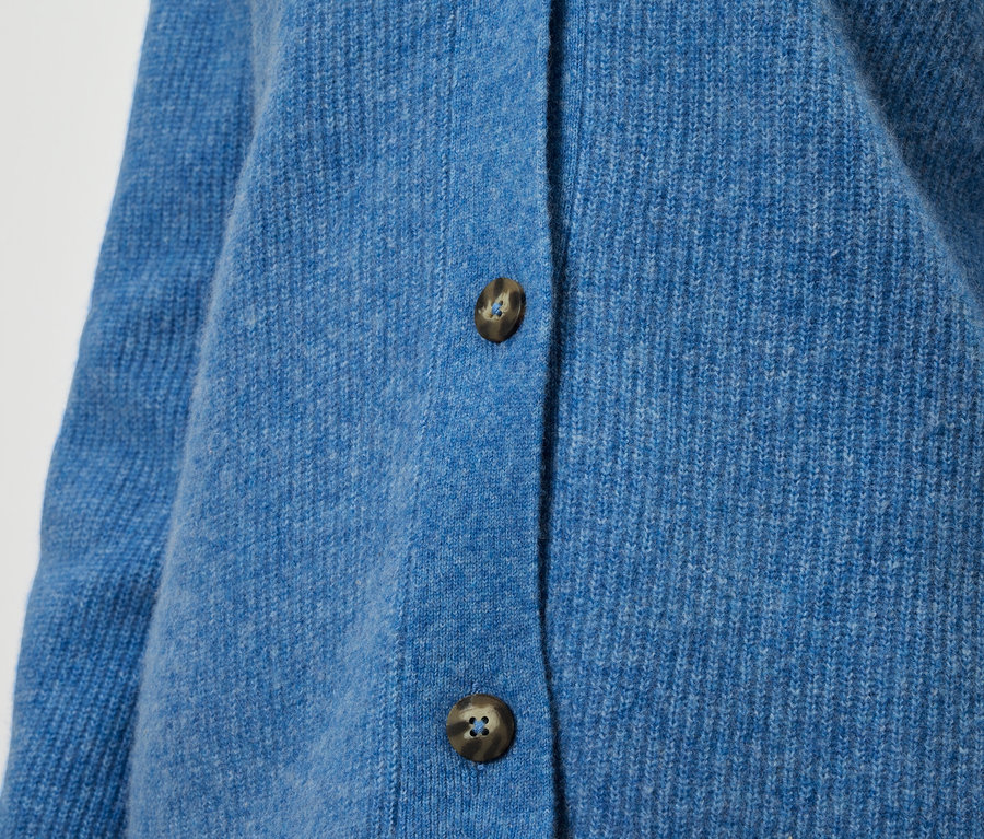 Gros plan sur un cardigan bleu en tricot avec des boutons marron.