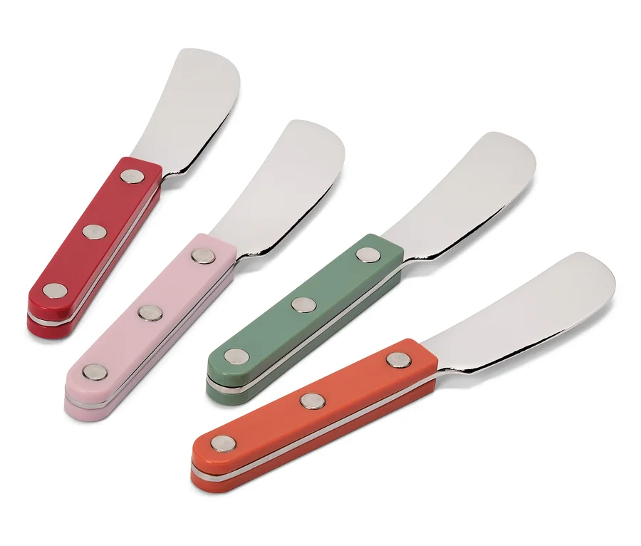 Quatre couteaux à beurre avec des manches colorés en rouge, rose, vert et orange sont disposés en diagonale sur un fond blanc.