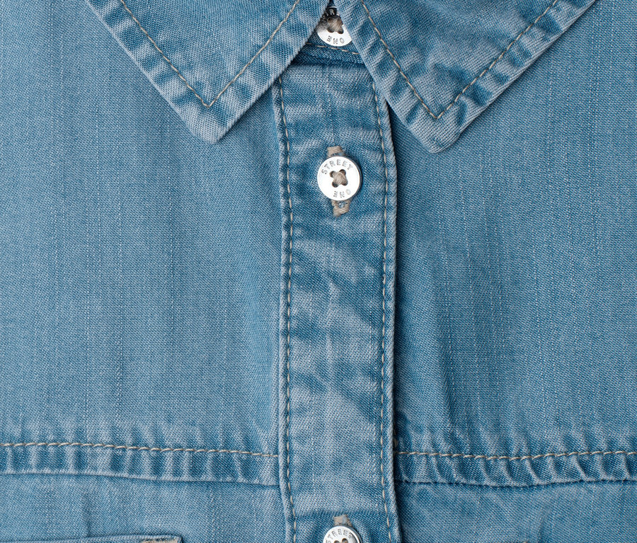 Gros plan sur une robe en jean Street One bleu clair avec col et patte de boutonnage. Les boutons blancs portent l'inscription 'Street One'.