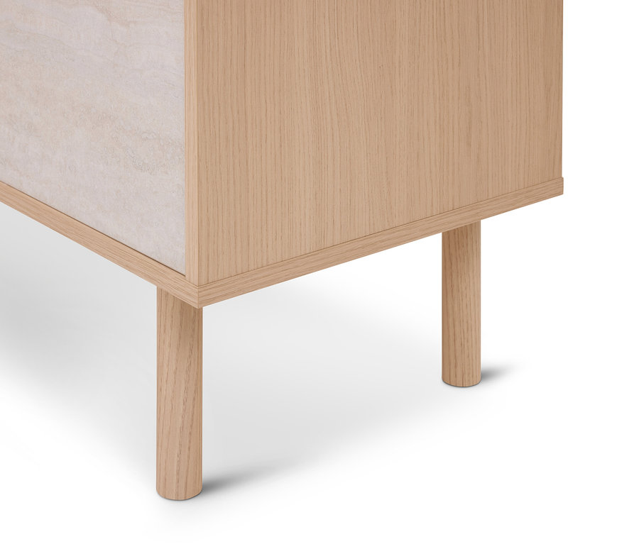 Coin inférieur d'un meuble avec un cadre en bois clair et deux pieds ronds, un panneau latéral en matériau clair et texturé.