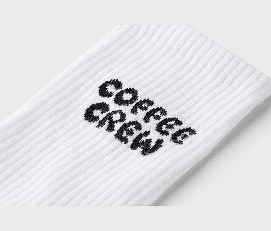 Gros plan d'une chaussette blanche avec l'inscription noire "Coffee Crew".