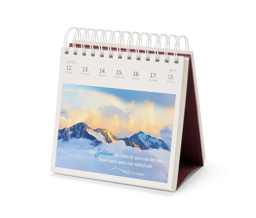Un calendrier de bureau ouvert affiche la semaine du 12 au 18 avril, avec une image de montagnes enneigées dans les nuages et une citation d'Isa Miranda.