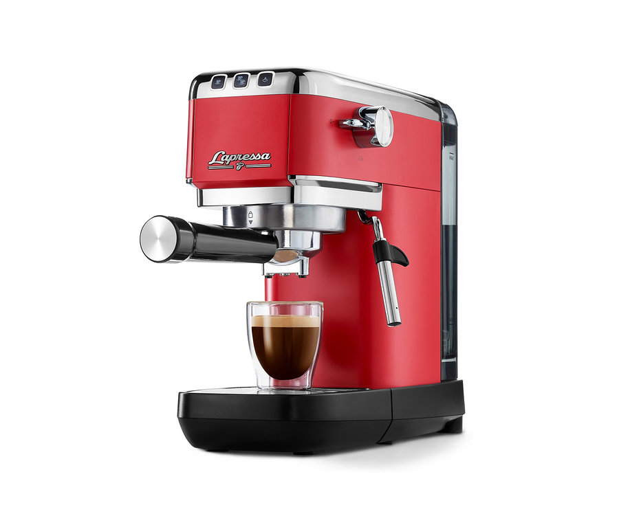 Machine à porte-filtre « Lapressa » rouge, versant du café dans une tasse en verre transparent, avec des accents chromés et une buse vapeur.