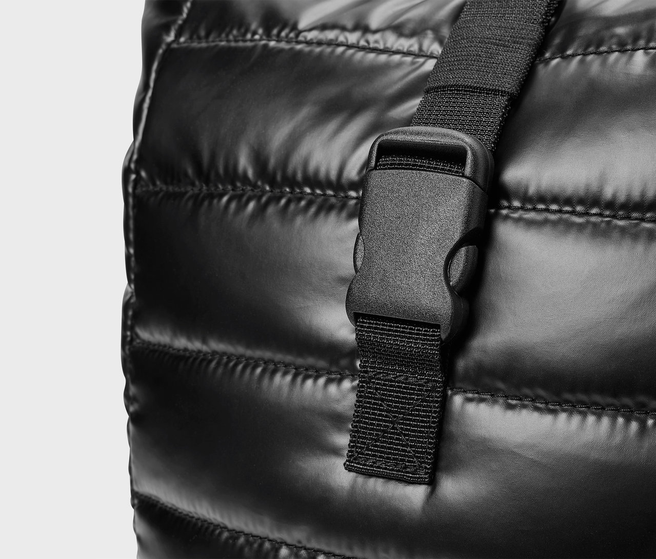 Gros plan d'un sac noir matelassé avec une boucle en plastique.