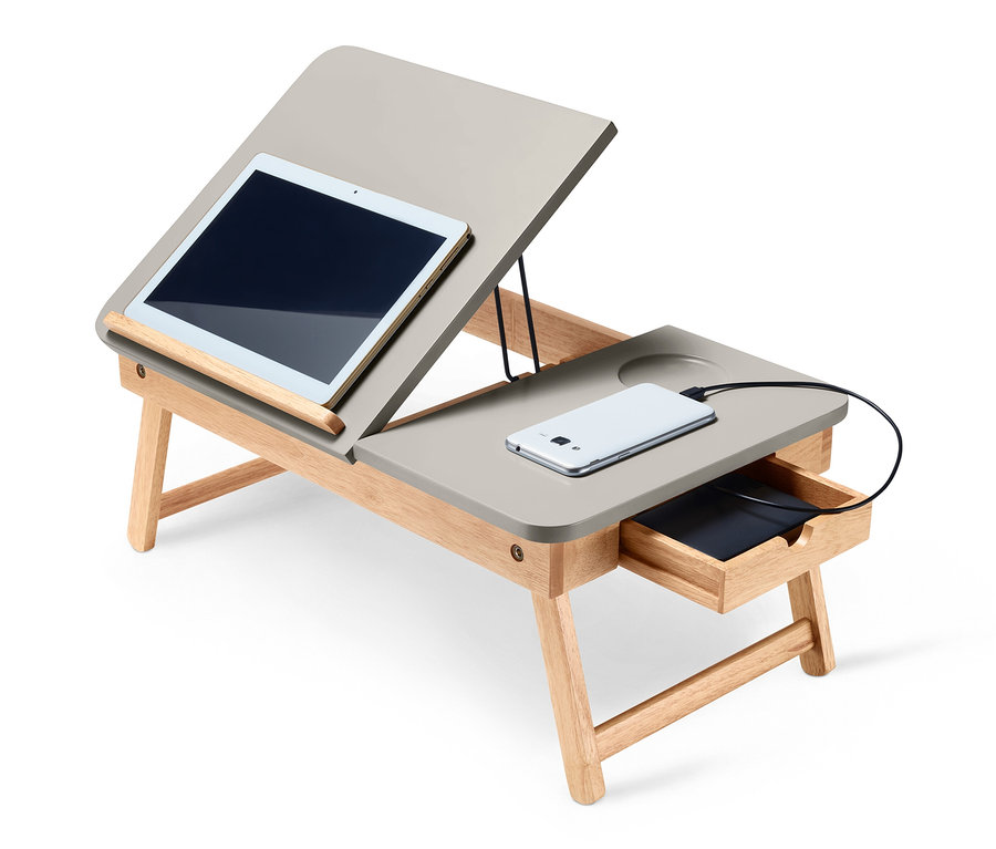 Une tablette et un téléphone portable sont posés sur une table de lit en bois.