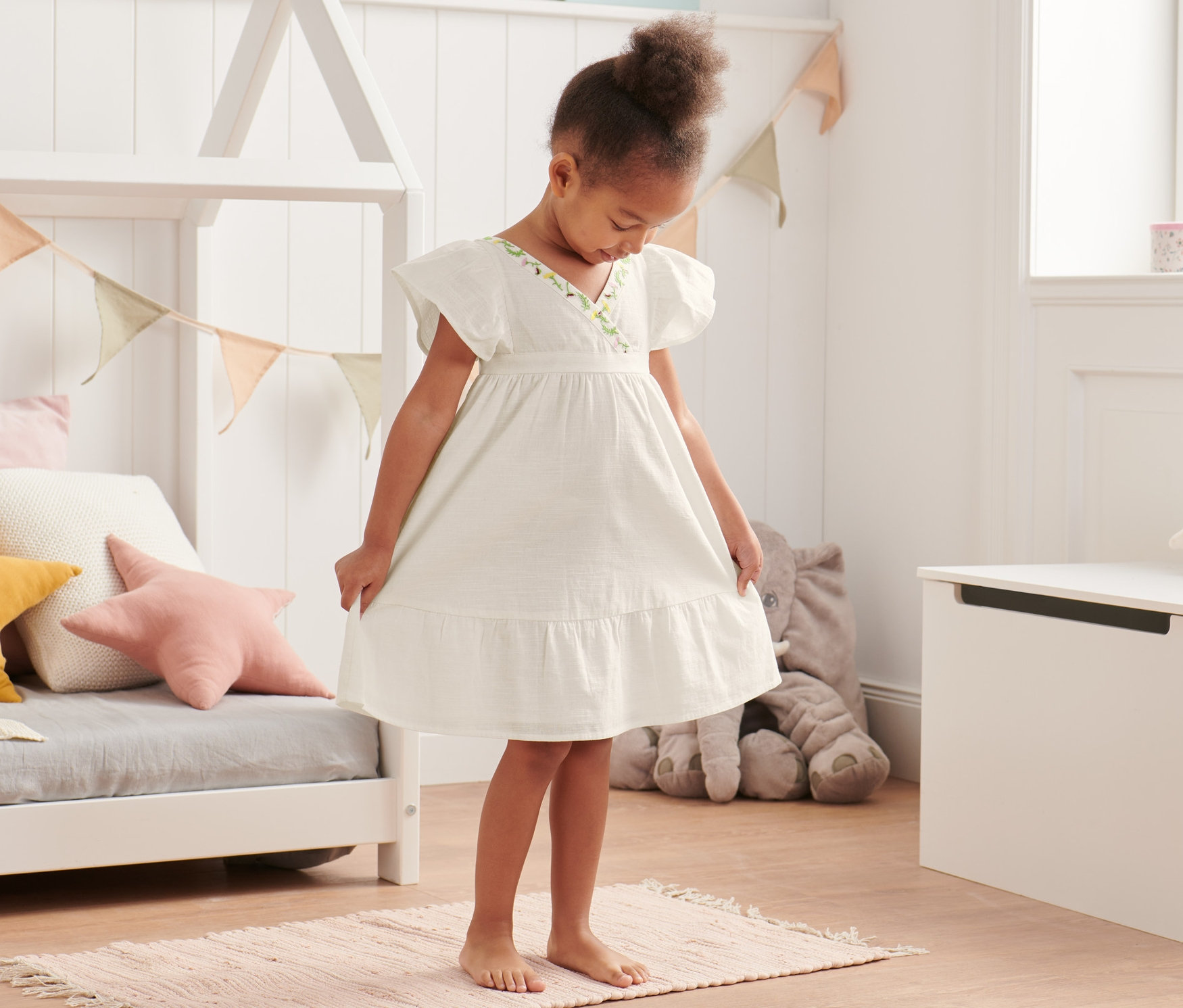 Une fille se tient sur un tapis et porte une robe tissée en coton bio.