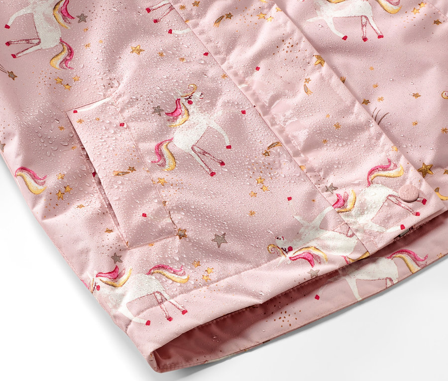 Détail d'une veste de pluie thermique rose pour enfant avec des motifs de licornes et d'étoiles.