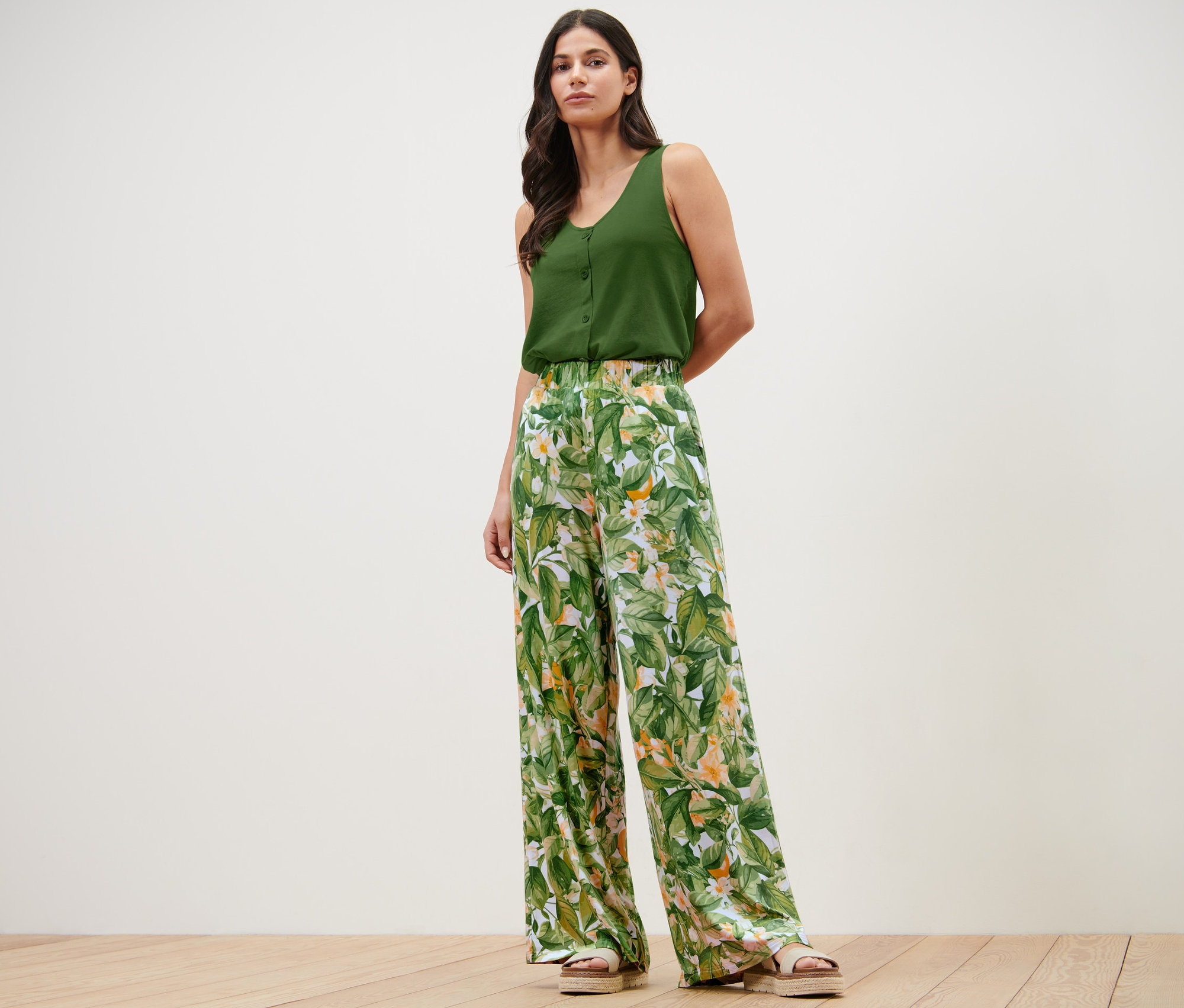 Femme posant dans un haut vert et un pantalon palazzo imprimé.