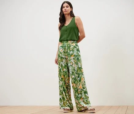 Femme posant dans un haut vert et un pantalon palazzo imprimé.