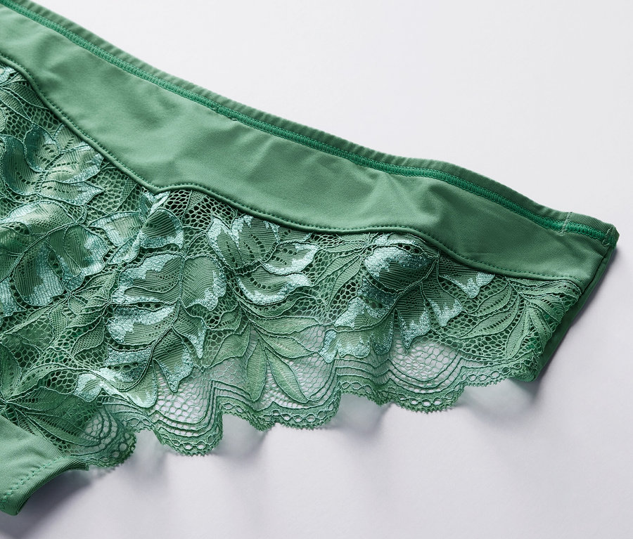 Gros plan sur un 4 Slips brésiliens verts avec de la dentelle florale sur un fond blanc.