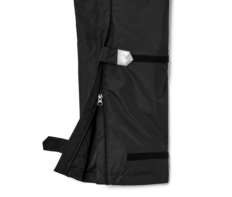 Gros plan sur un pantalon de pluie unisexe high-tech noir avec une fermeture éclair ouverte sur le côté.