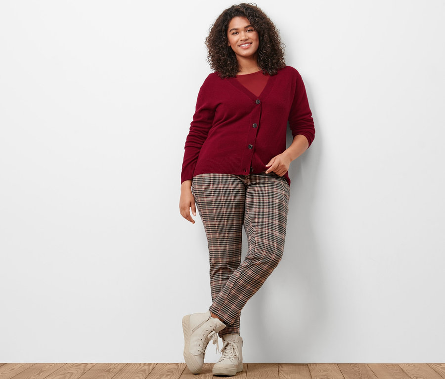 Femme posant en gilet en maille avec du cachemire, T-shirt manches 3/4 rouge bordeaux et jogpant motif pied-de-poule.