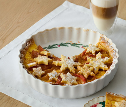 Tarte dans un moule à tarte avec des étoiles en pâte et un verre de café latte.
