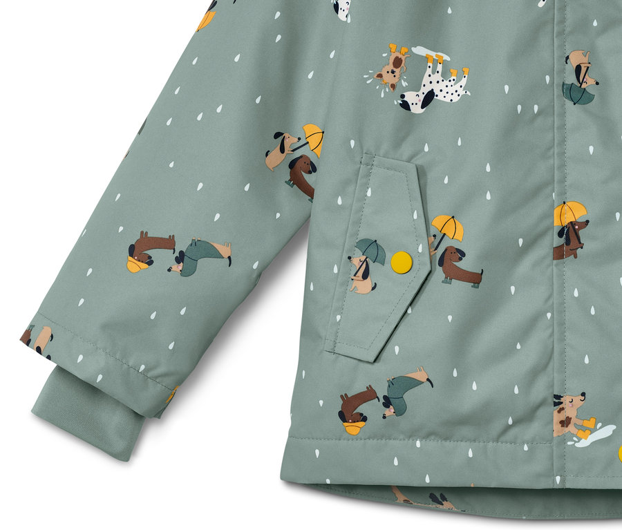 Détail d'une veste de pluie thermique pour enfant avec motif de chiens et de gouttes.