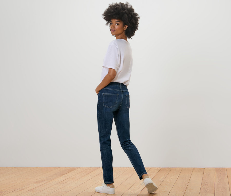 Femme regardant par-dessus son épaule et posant en jean slim – Coupe « Emma », bleu foncé.