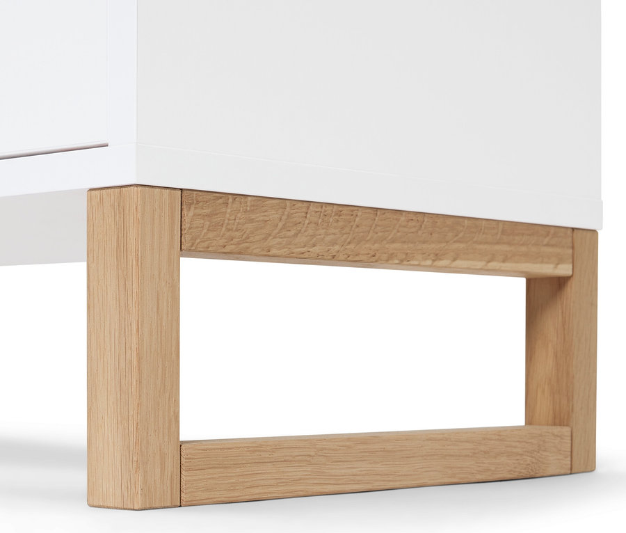 Détail d'un meuble de rangement avec 2 tiroirs et 2 portes, armoire blanche avec pieds en bois.