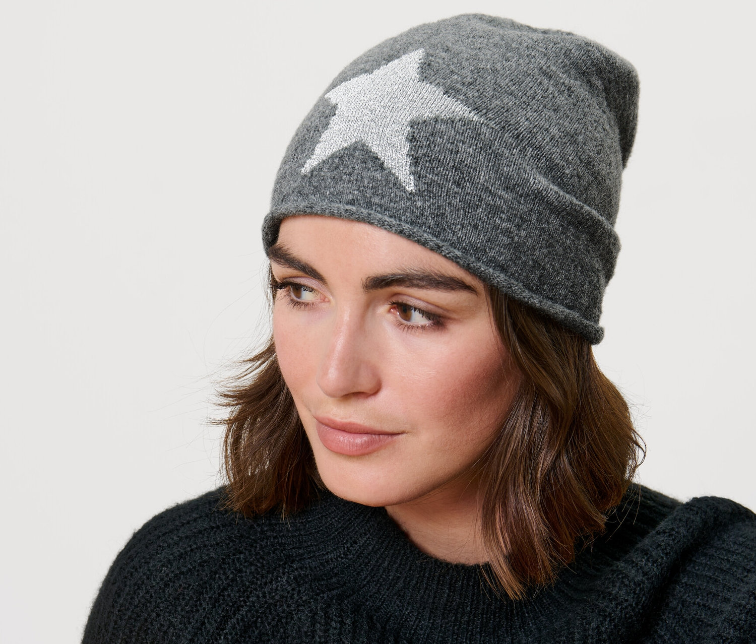 Une femme portant un beanie en maille fine avec une étoile scintillante.