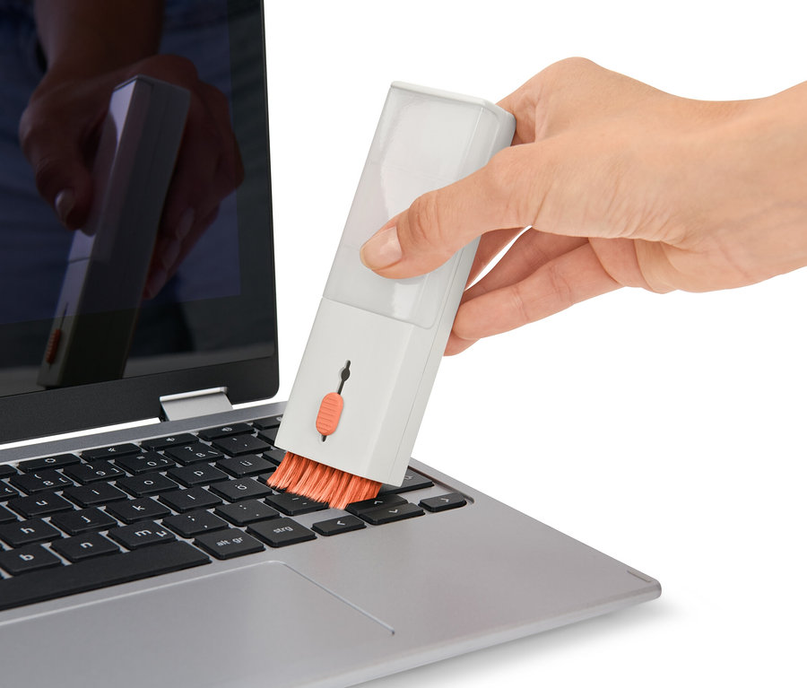 Une main nettoie le clavier d'un ordinateur portable avec un set de nettoyage de bureau 4 en 1.