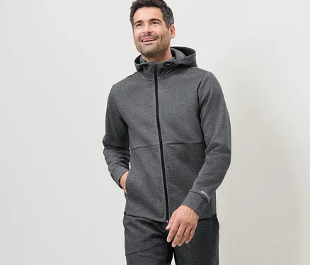 Un homme porte une veste technique en sweat grise.