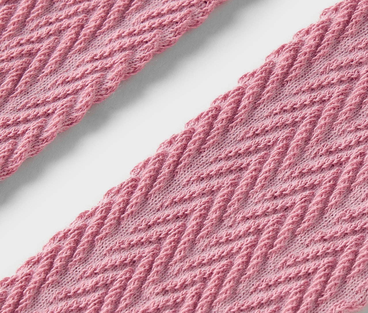 Gros plan de deux bandes de tissu rose avec un motif en zigzag.
