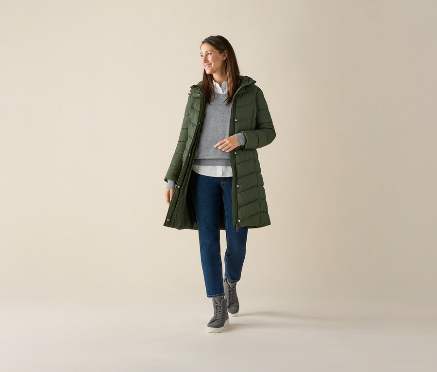 Femme portant un pull gris en maille fine de laine mérinos, une veste verte et un jean.