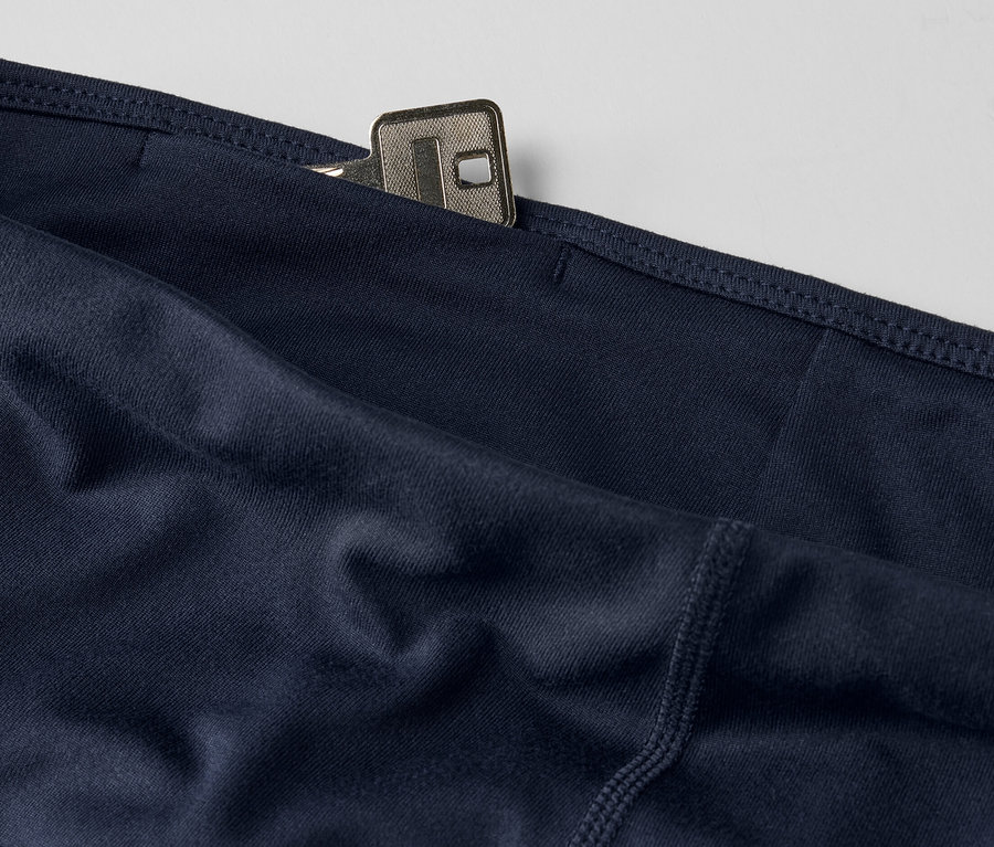 Gros plan sur un collant de sport 3/4 bleu foncé avec une clé dans la poche.