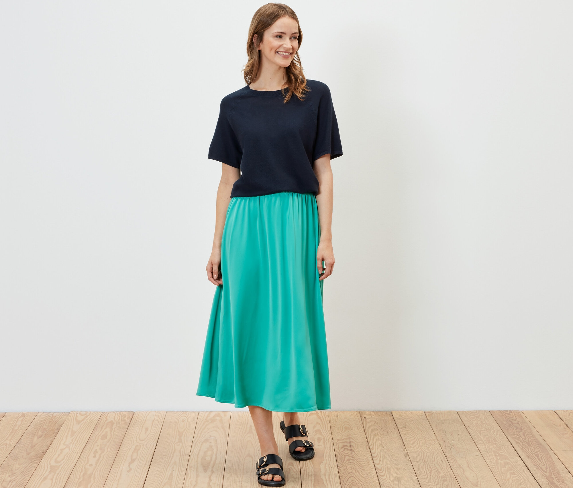 Femme posant en T-shirt en maille fine bleu marine et jupe turquoise.