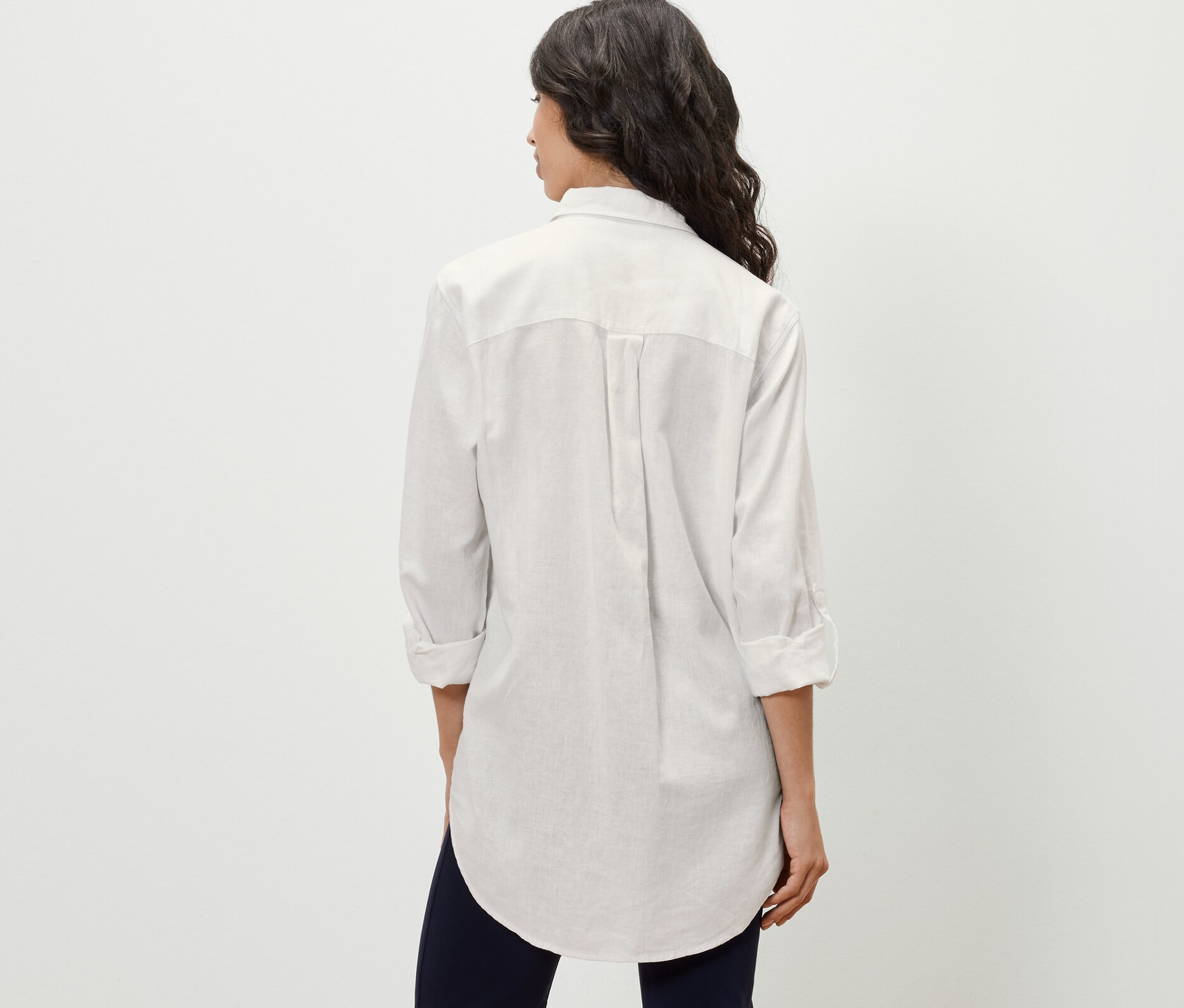 Femme vue de dos portant une blouse longue en lin, blanche.