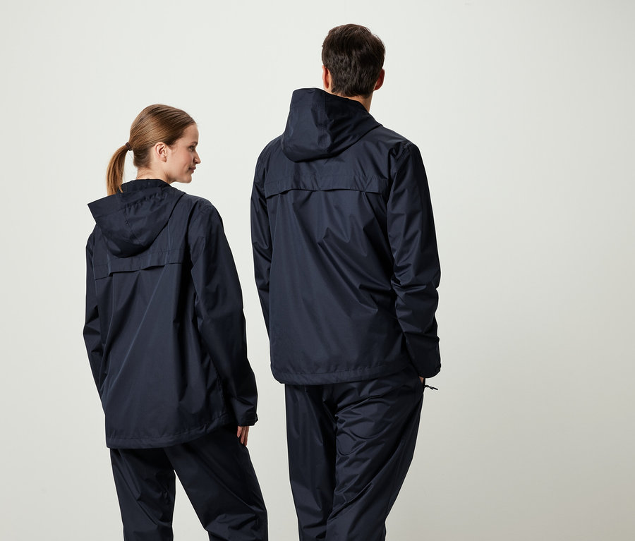 Deux personnes dos à la caméra portant des vestes à capuche bleu marine et des pantalons assortis.