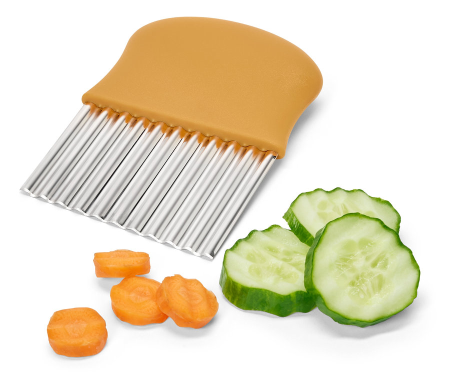 Coupe-légumes ondulé avec manche orange à côté de concombre et de carottes coupés.