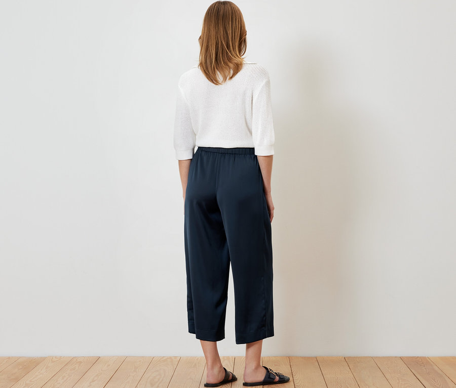 Femme vue de dos portant un pantalon en satin bleu marine.