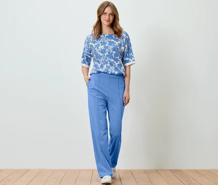Femme posant dans un sweat-shirt imprimé bleu clair et un pantalon bleu.